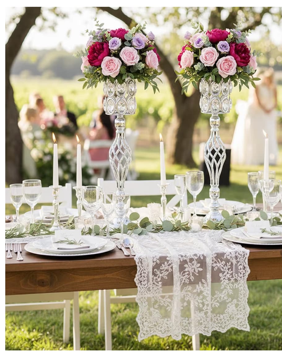 Elegant outdoor table setting featuring pink floral centerpieces, white lace runner, and silver candle holders.