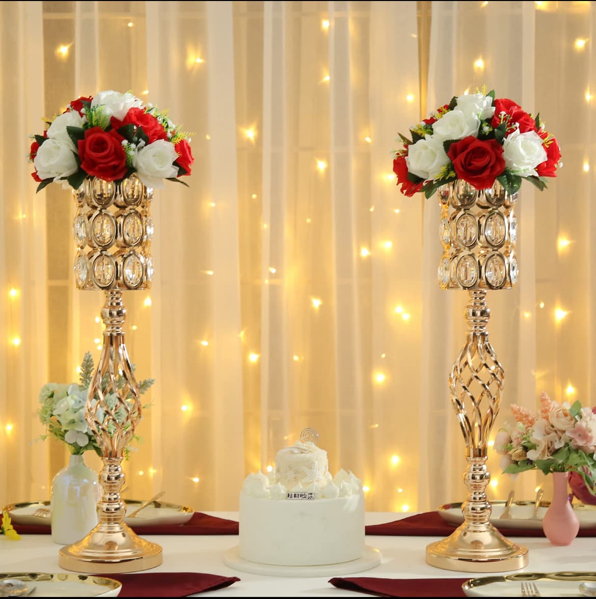 Two gold crystal flower stands with red and white roses flanking a white cake.
