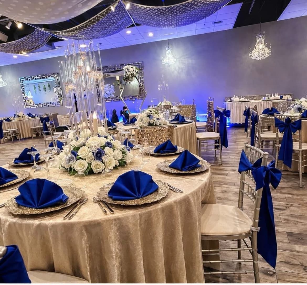 Elegant banquet tables with champagne velvet cloths, royal blue napkins, and white rose centerpieces.
