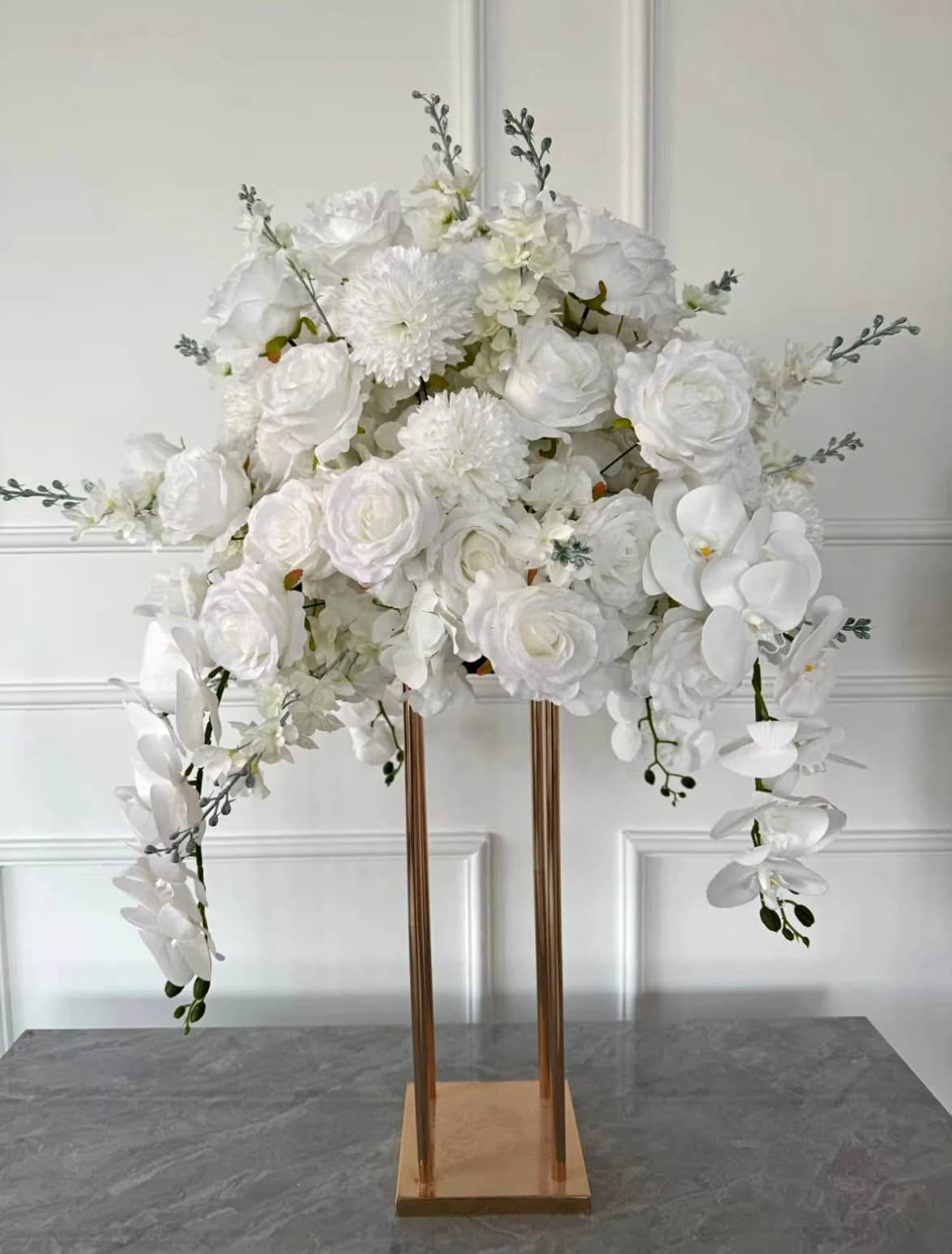 Elegant white floral centerpiece with roses and cascading orchids on a tall gold metal stand.