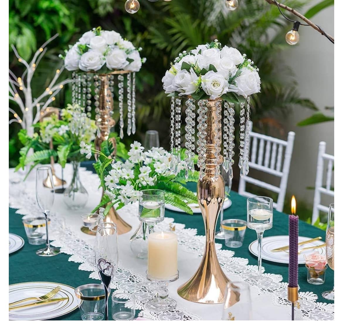 Elegant table setting featuring tall gold centerpieces with white roses, crystal beads, and lit candles.