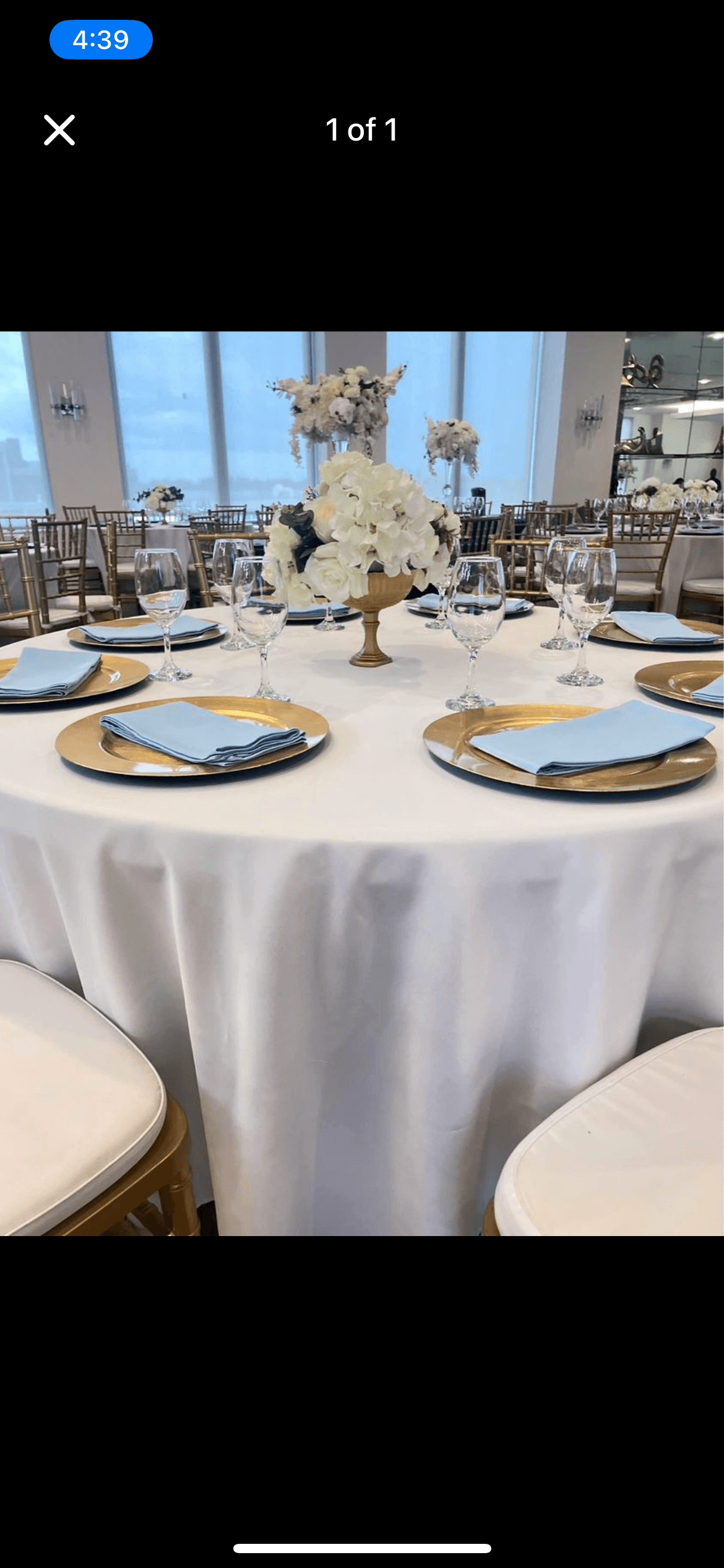 Elegant round table with gold chargers, light blue napkins, and a white floral centerpiece.